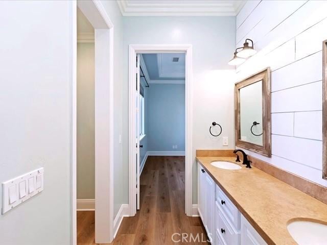 bathroom with crown molding, wood-type flooring, and vanity