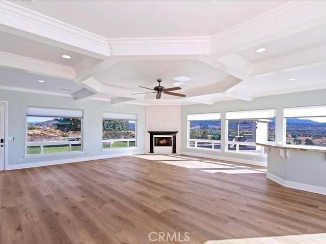 unfurnished living room with beam ceiling, a healthy amount of sunlight, coffered ceiling, and light hardwood / wood-style floors