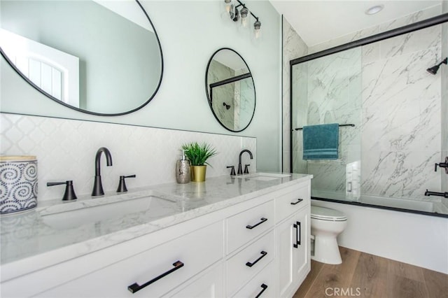 full bathroom with enclosed tub / shower combo, hardwood / wood-style floors, vanity, and decorative backsplash