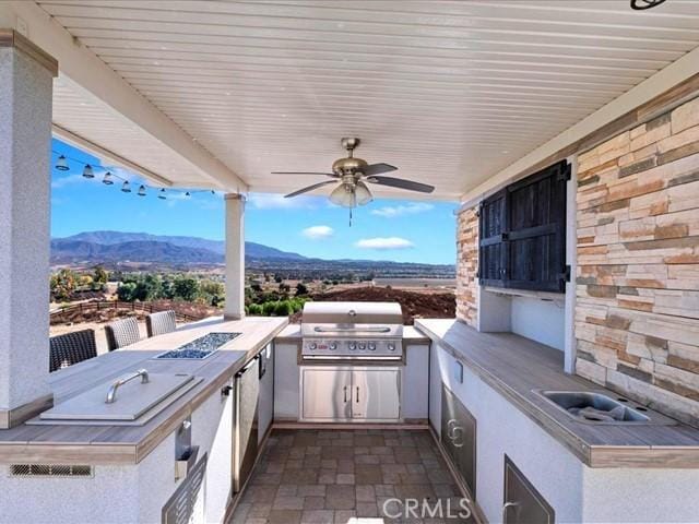 view of patio / terrace with area for grilling, a mountain view, and ceiling fan