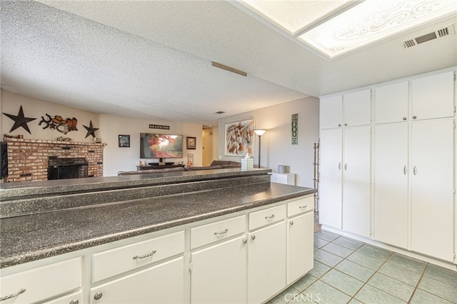 kitchen with white cabinetry, a fireplace, light tile patterned floors, and a textured ceiling