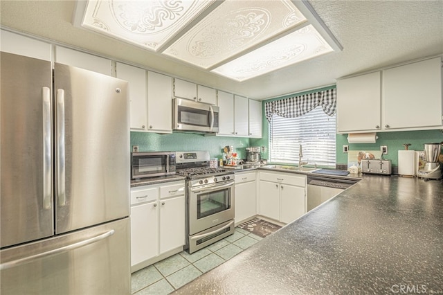 kitchen with sink, light tile patterned flooring, a textured ceiling, white cabinets, and appliances with stainless steel finishes