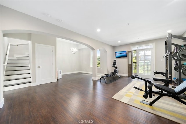 workout area with a chandelier and dark wood-type flooring