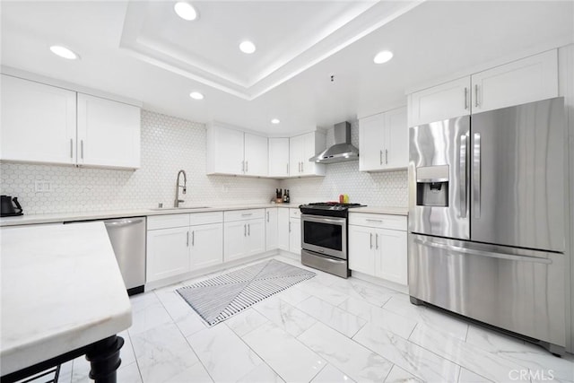 kitchen featuring appliances with stainless steel finishes, backsplash, sink, wall chimney range hood, and white cabinetry