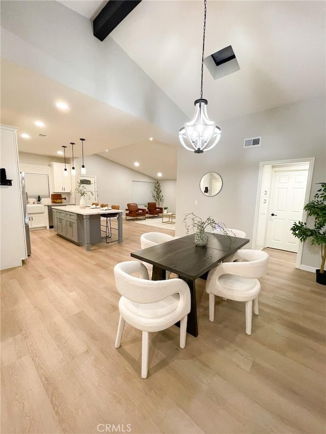 dining area featuring an inviting chandelier, lofted ceiling with beams, and light wood-type flooring