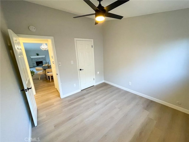 unfurnished bedroom featuring a fireplace, light wood-type flooring, and ceiling fan