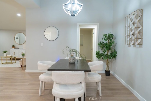 dining area with light wood-type flooring, a high ceiling, and a chandelier