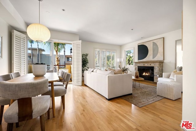 living room with a brick fireplace and light hardwood / wood-style flooring