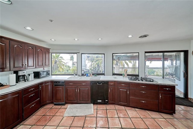 kitchen featuring dark brown cabinetry, light tile patterned floors, and black appliances