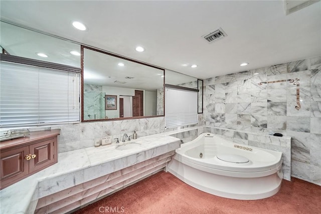 bathroom with vanity, a bathtub, and tile walls