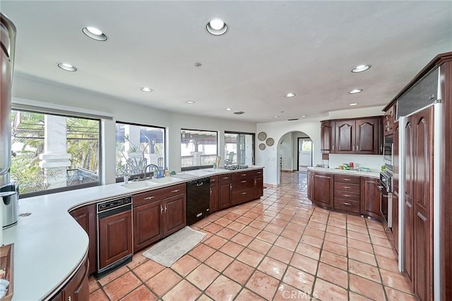 kitchen with dark brown cabinets, sink, light tile patterned floors, and stainless steel appliances