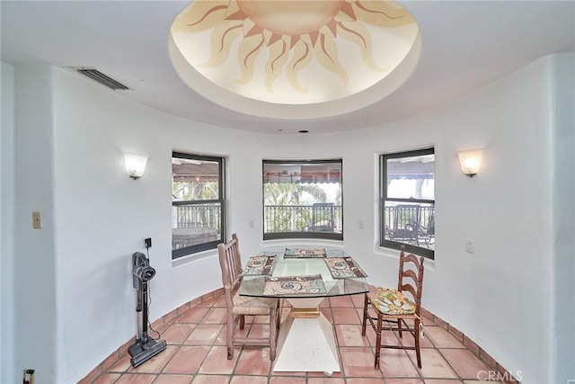 dining area with light tile patterned flooring, a wealth of natural light, and a tray ceiling