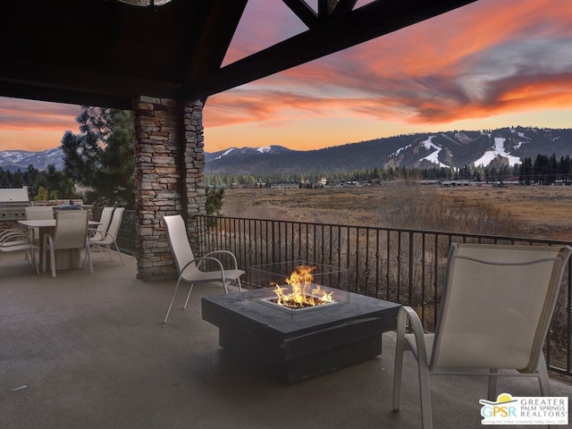 patio terrace at dusk featuring a fire pit and a mountain view