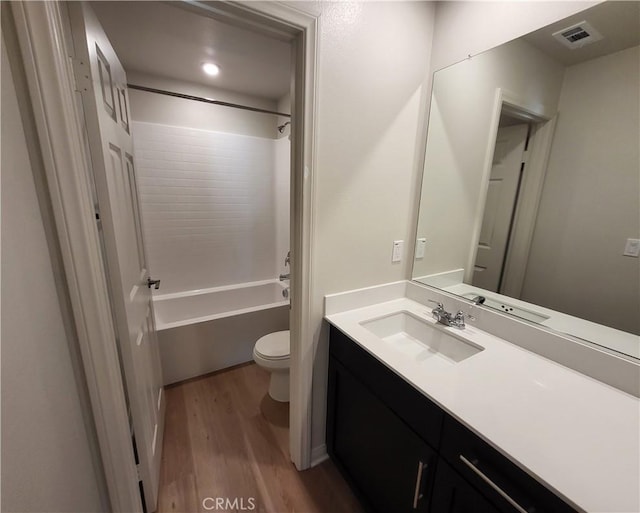 full bathroom with hardwood / wood-style flooring, vanity, toilet, and washtub / shower combination