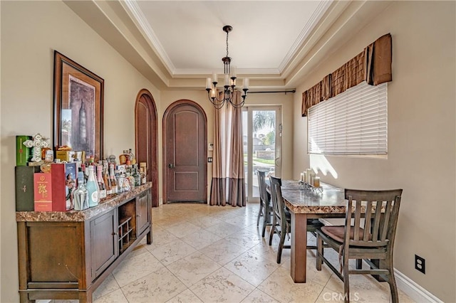 dining area featuring a raised ceiling, crown molding, and an inviting chandelier