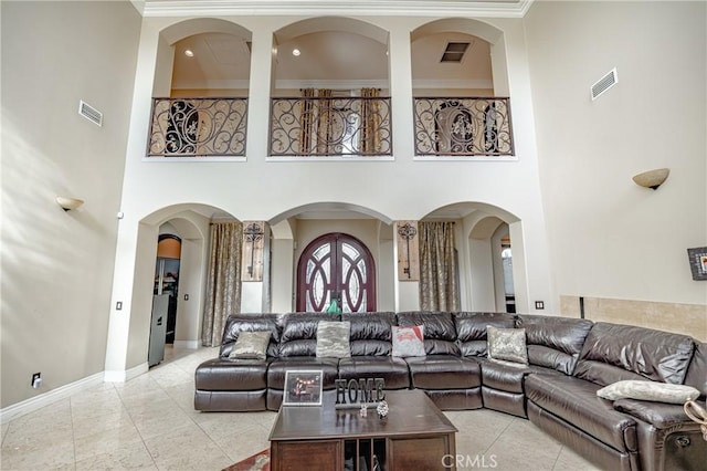 tiled living room featuring french doors, a towering ceiling, and crown molding