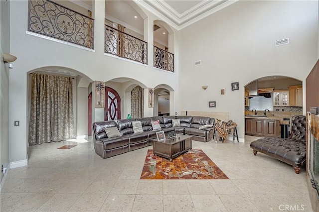 tiled living room featuring sink, crown molding, and a high ceiling