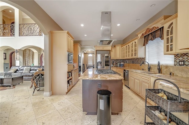 kitchen featuring island exhaust hood, appliances with stainless steel finishes, tasteful backsplash, light stone counters, and a center island