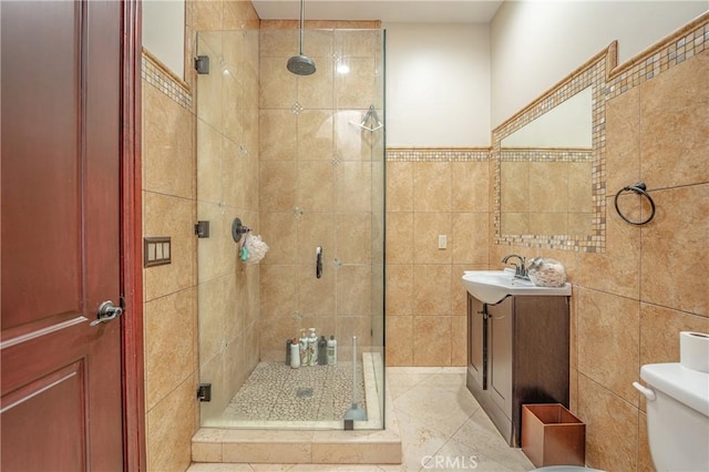 bathroom featuring tile patterned floors, walk in shower, vanity, tile walls, and toilet