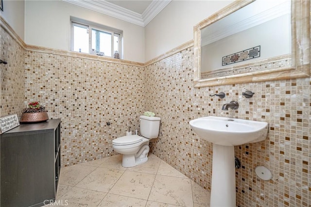 bathroom with tile patterned flooring, toilet, tile walls, and crown molding