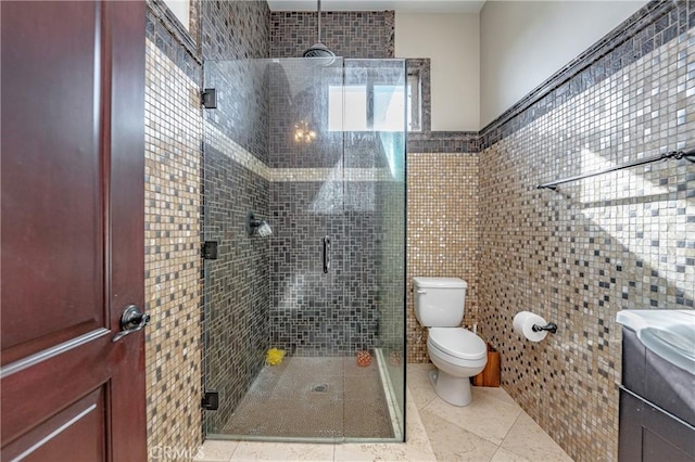 bathroom featuring vanity, toilet, tile walls, and a shower with shower door