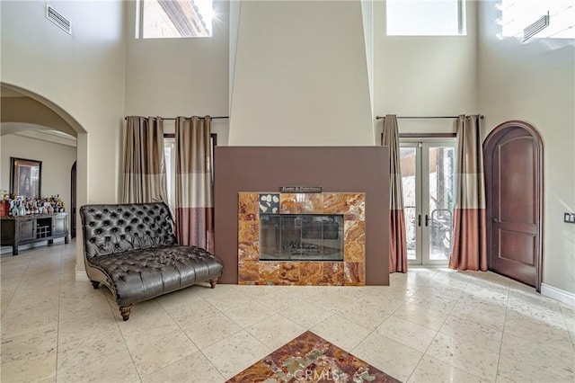 living room featuring a high end fireplace, a high ceiling, and french doors