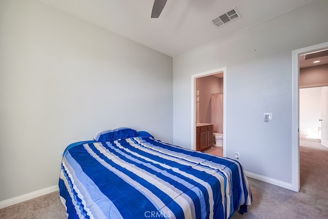 bedroom with ceiling fan, light colored carpet, and ensuite bath