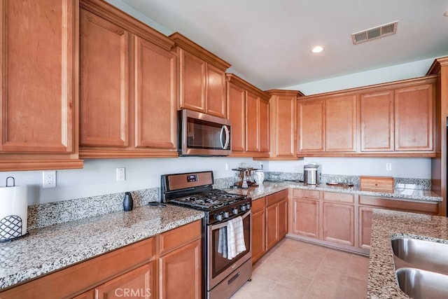 kitchen with light stone countertops, stainless steel appliances, and sink