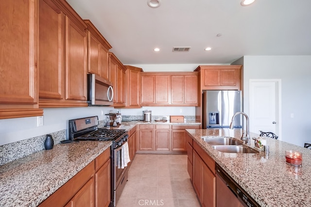 kitchen featuring stainless steel appliances, light stone counters, and sink