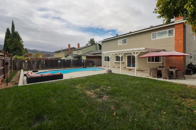 back of property with a fenced in pool, a patio area, and a lawn