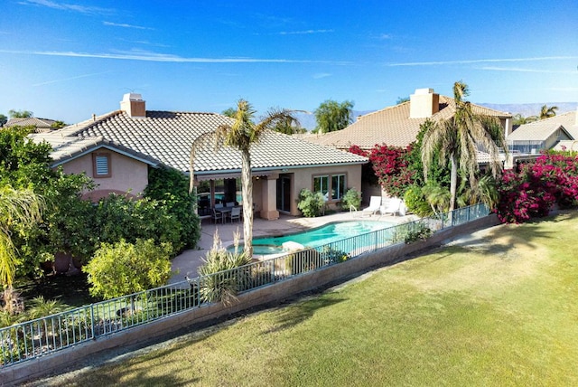 rear view of property with a fenced in pool, a patio area, and a lawn