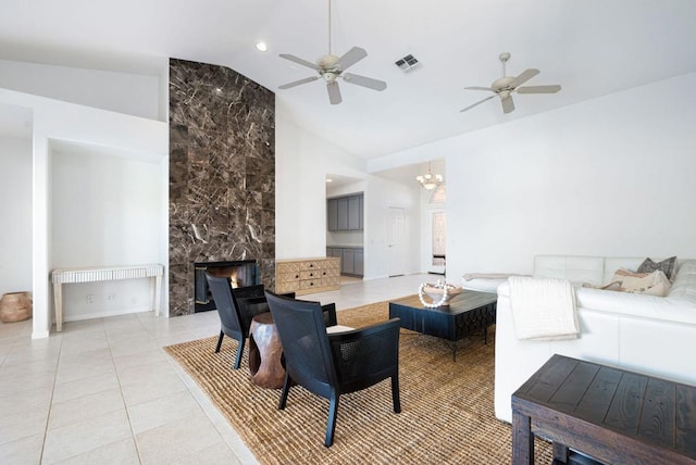 living room featuring ceiling fan with notable chandelier, light tile patterned floors, a premium fireplace, and vaulted ceiling