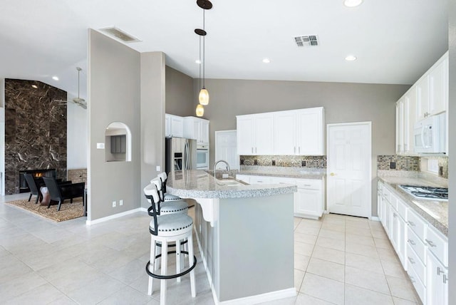 kitchen with a kitchen island with sink, hanging light fixtures, sink, appliances with stainless steel finishes, and white cabinetry