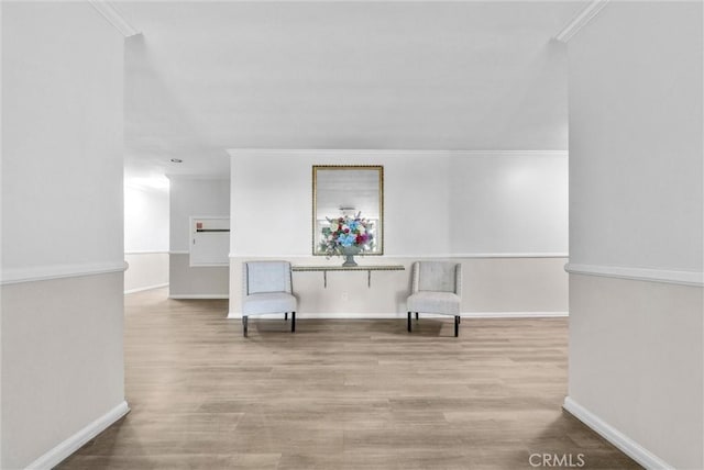 sitting room featuring baseboards, light wood finished floors, and crown molding