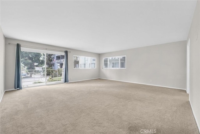 unfurnished room featuring light carpet and baseboards