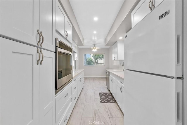 kitchen featuring light countertops, stainless steel dishwasher, freestanding refrigerator, and white cabinets