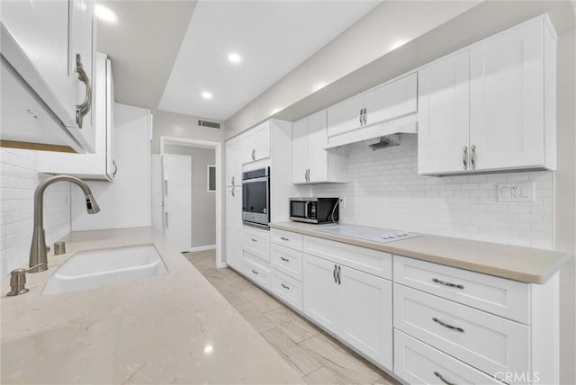 kitchen with tasteful backsplash, visible vents, stainless steel appliances, white cabinetry, and a sink