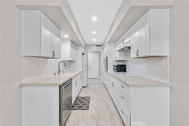 kitchen featuring appliances with stainless steel finishes, white cabinets, light countertops, and a sink