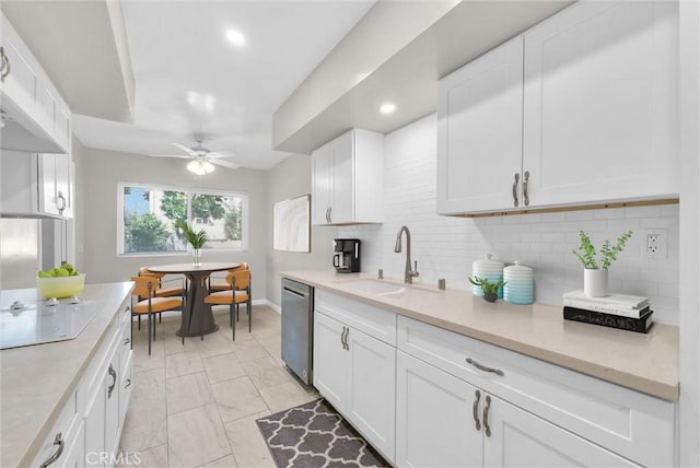 kitchen featuring tasteful backsplash, light countertops, stainless steel dishwasher, white cabinetry, and a sink