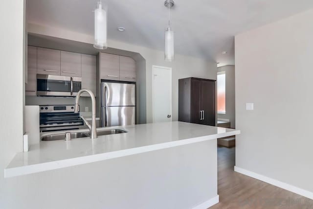 kitchen with sink, hanging light fixtures, stainless steel appliances, dark hardwood / wood-style floors, and kitchen peninsula