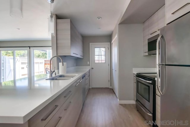 kitchen with hanging light fixtures, a healthy amount of sunlight, sink, and stainless steel appliances