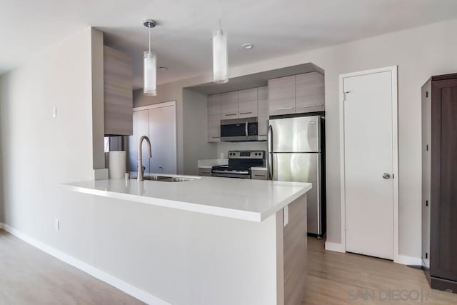 kitchen with kitchen peninsula, light hardwood / wood-style floors, stainless steel appliances, decorative light fixtures, and gray cabinets