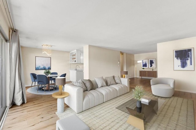 living room featuring a notable chandelier, light wood-type flooring, and sink