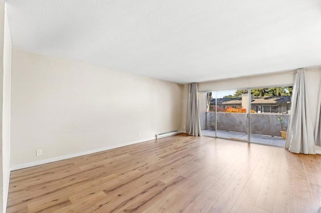 empty room featuring a baseboard heating unit and light wood-type flooring