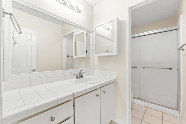 bathroom featuring toilet, an enclosed shower, tile patterned flooring, and vanity