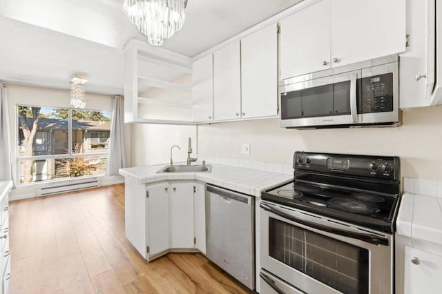 kitchen with appliances with stainless steel finishes, white cabinets, and tile counters