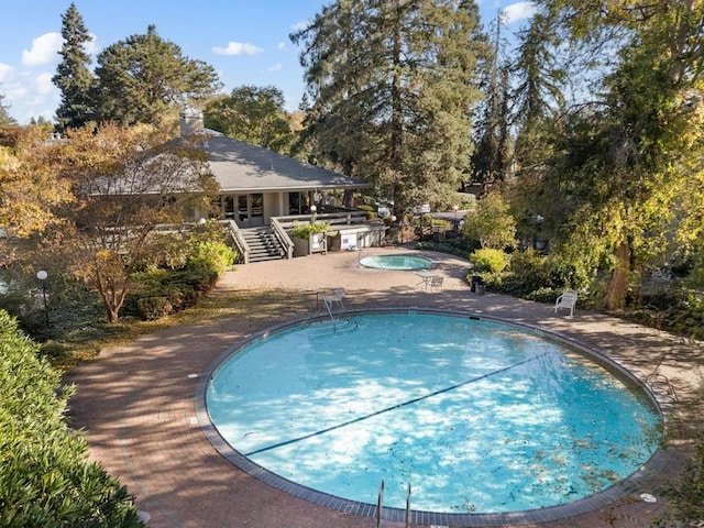 view of swimming pool featuring a patio and an in ground hot tub