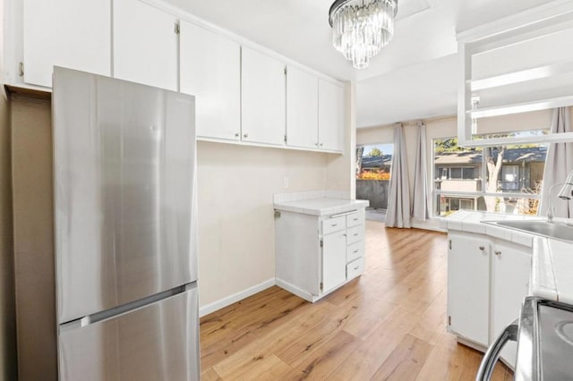 kitchen with white cabinets, stainless steel fridge, and tile countertops