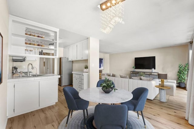 dining room with sink, light hardwood / wood-style floors, and a chandelier