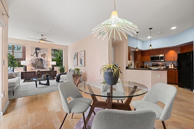 dining area with ceiling fan with notable chandelier and light wood-type flooring